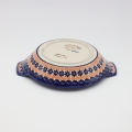 Round baking dish with handles made of Boleslawiec pottery.